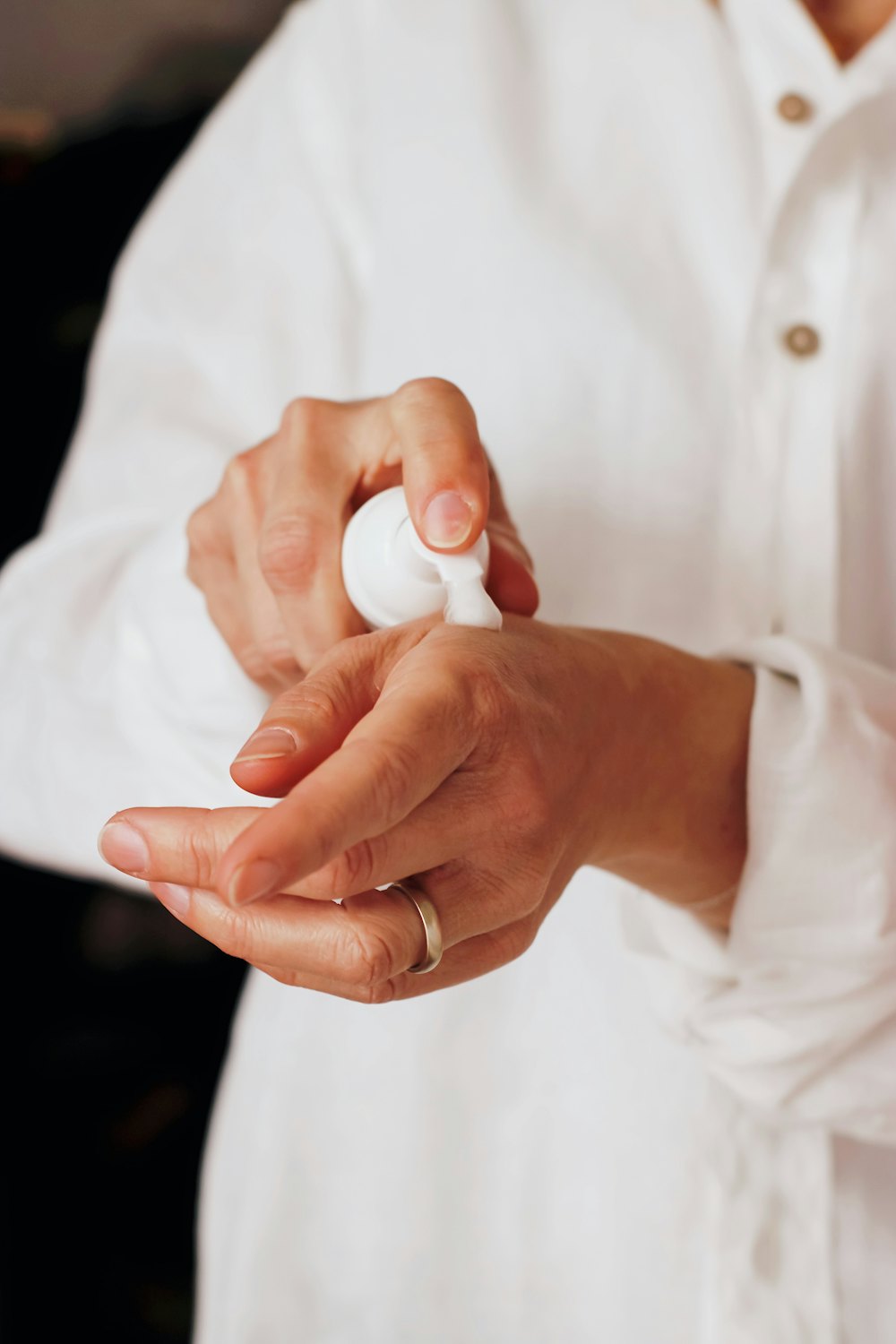 Hands pressing lotion from a white pump bottle
