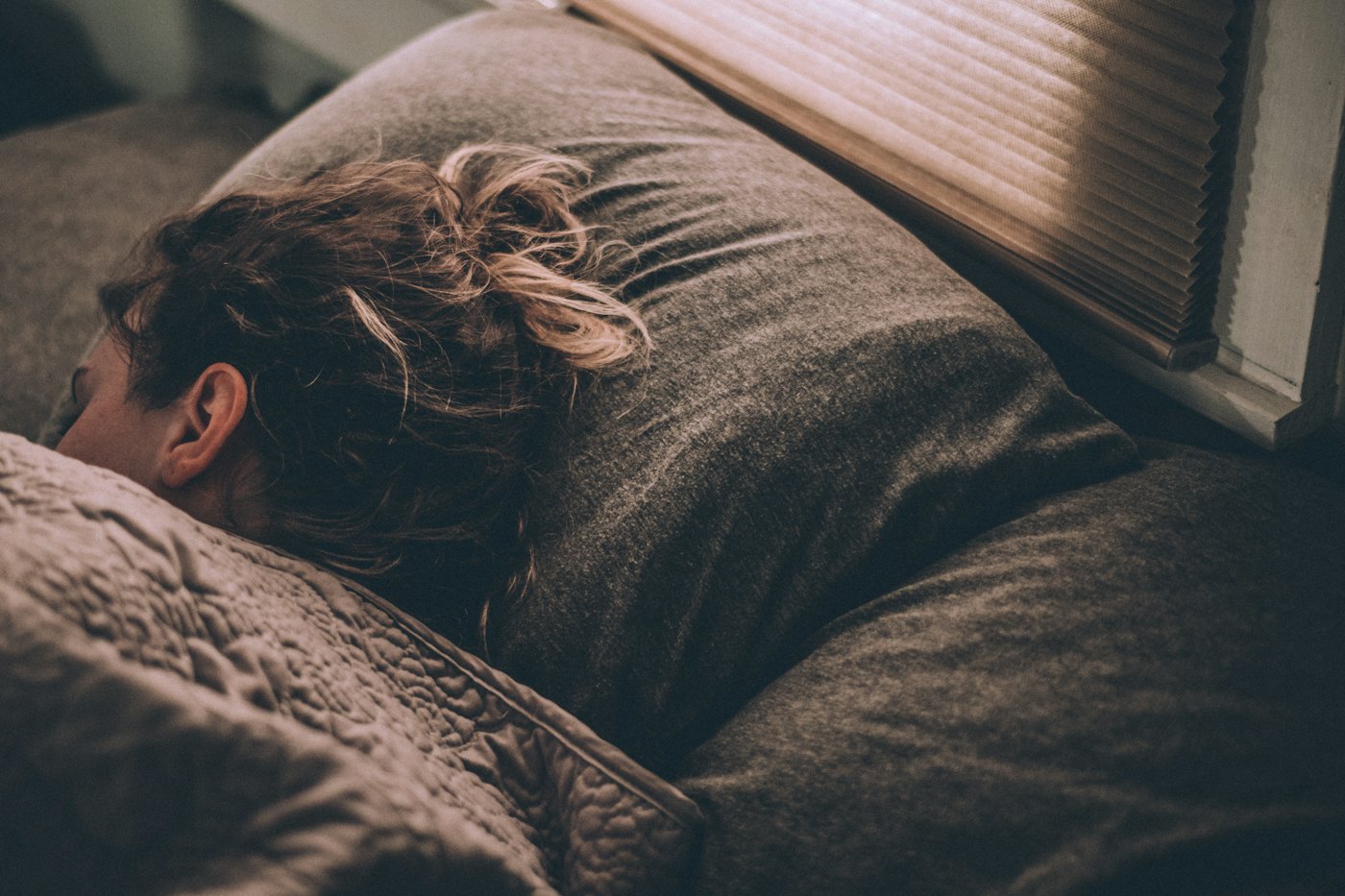 A woman asleep in bed under heavy grey blankets
