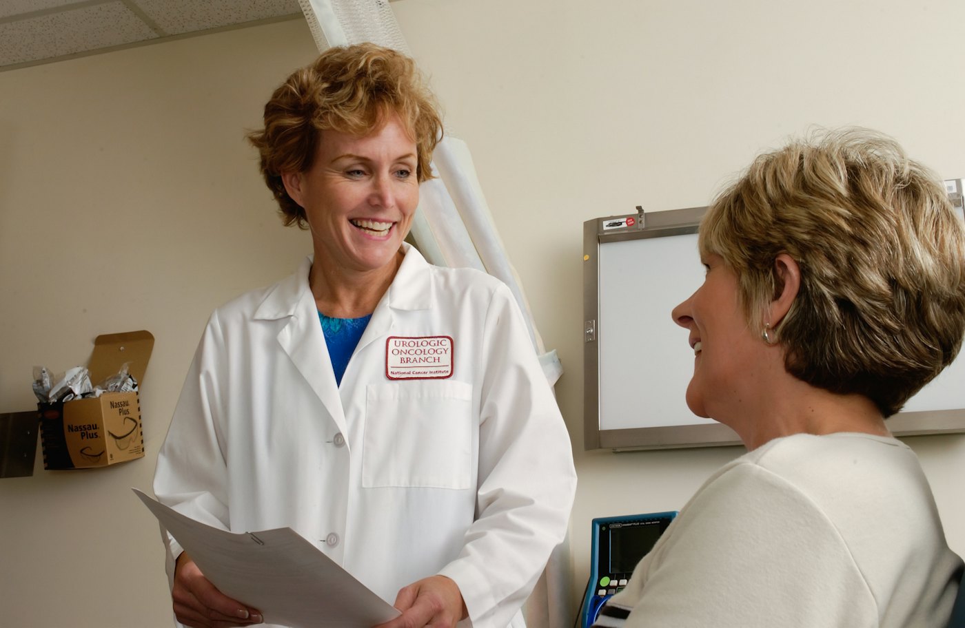 A smiling doctor talking with a patient in a clinic room